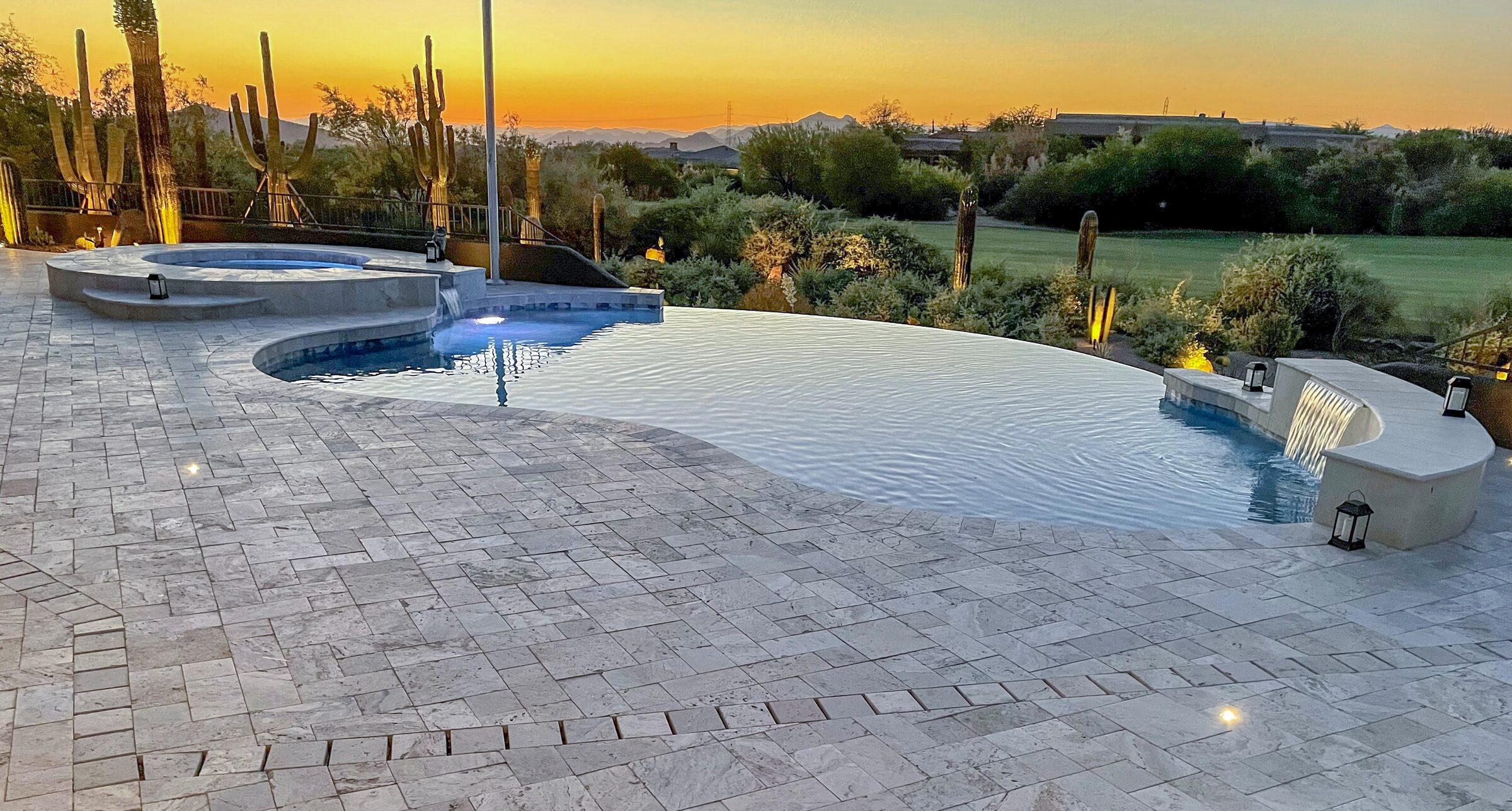 Luxury infinity edge pool with integrated spa overlooking Sonoran Desert landscape with saguaro cacti at golden hour in Scottsdale